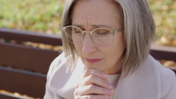 一个戴着眼镜的害怕女人坐在公园的长椅上 感到紧张和恐慌 — 图库视频影像