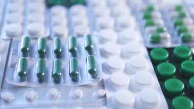 Masada bir sürü beyaz ve yeşil hap ve tablet var. Kadınlar için büyük bir hormonal ilaç seçimi. Hamilelik planlamasından önce hormonal seviyelerin normalleşmesi.