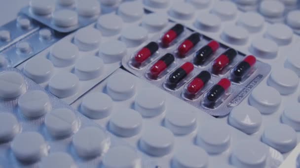 许多不同的药丸水泡摆在桌上 一个水泡里的药丸和其他的药丸不同 损坏或替换了药品 这些药品没有通过质量控制 — 图库视频影像