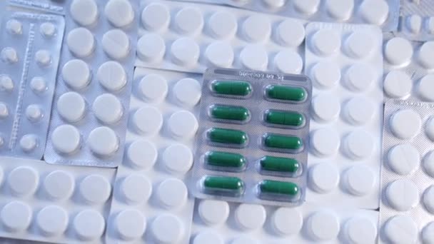 白い丸い錠剤の間に横たわる緑の錠剤とブリスター それらの欠乏を排除し 食事を最適化するために生物学的に活性な物質の追加のソースとして使用される栄養補助食品 — ストック動画