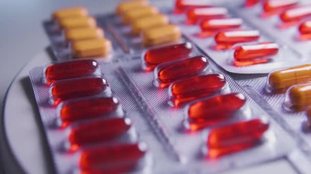 オレンジと赤のカプセルをテーブルの上に寝そべってクローズアップ医薬品水疱 製薬会社は積極的な成分 広告と新しい医薬品の生産に従事しています — ストック動画