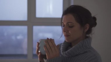 Sıcak, rahat kazak giyen, sıcak aromalı kahve ya da çay içen, evde eğlenen, pencereye bakıp hayal kuran, ilham veren romantik, güzel bir kadın.