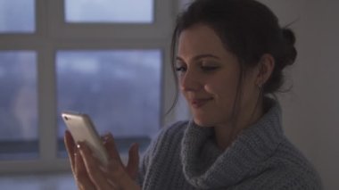 Genç bir kadın sosyal ağlarda akıllı telefonlarda haberlere doğru kayıyor ve gülümsüyor, haberleri okuyor, yorumluyor ve notlarını veriyor.