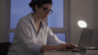 Genç bir kadın göğsünde ani bir ağrı hissediyor laptopla çalışıyor, kalp krizi riski var.