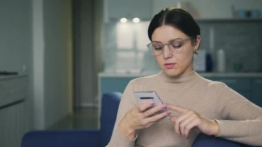 Sinirli esmer kadın faturalarını internet üzerinden ödeyerek akıllı telefona başvuruyor. Kredi almak ya da kredi vermek için yeterli parası yok.