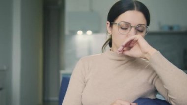 Genç esmer kadın baş ağrısı ve migren krizi geçiriyor, adet belirtileri gösteriyor.