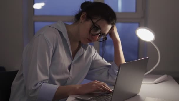ノートパソコンに片手で入力し 遅くまでエッセイに取り組んでいる退屈女性学生 — ストック動画