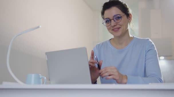 迷人害羞的年轻女子拿着笔记本电脑坐在工作场所的相机前摆姿势 — 图库视频影像