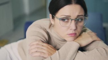 Depresyondaki işsiz kadın evde tek başına oturmuş pencereye bakıyor, oyalanıyor.