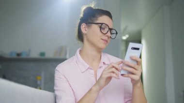 Şık gözlüklü ve tişörtlü güzel bir kadın akıllı telefonuyla radyo uygulamasını açıyor ve en sevdiği şarkının melodisini dinliyor ritme ayak uyduruyor, eğleniyor.