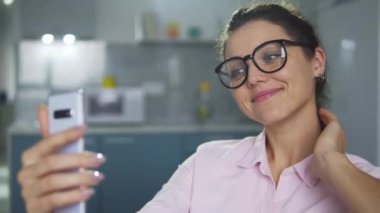 Gözlüklü mutlu bir kadın sosyal ağlar için poz veriyor ve selfie çekiyor, kadın blogcu video kaydediyor veya internetten yayın yapıyor, takipçilerle iletişim kuruyor.