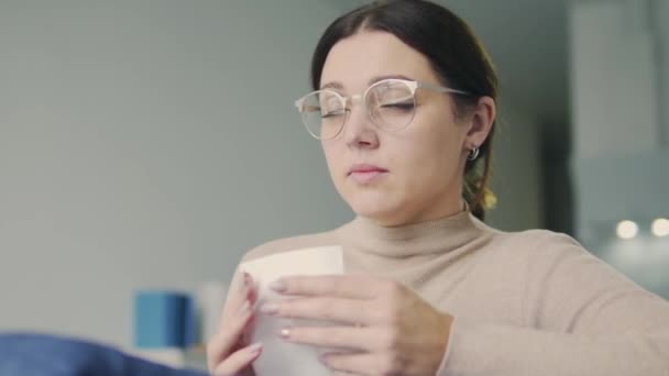 戴眼镜的女人打喷嚏，把鼻子吹进餐巾纸里，季节性感冒 — 图库视频影像