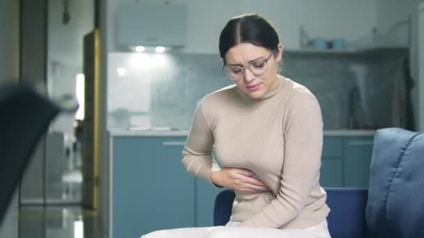 Νεαρή λεπτή γυναίκα που υποφέρει από οξύ πόνο στο στομάχι, συνοφρυωμένη από πόνο και αγγίζοντας επώδυνο μέρος, συνέπειες εξουθενωτικής δίαιτας, έξαρση γαστρίτιδας ή έλκους — Αρχείο Βίντεο