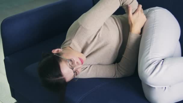 Mulher morena deitada no sofá e tocando dor de barriga sentindo dor de estômago terrível — Vídeo de Stock