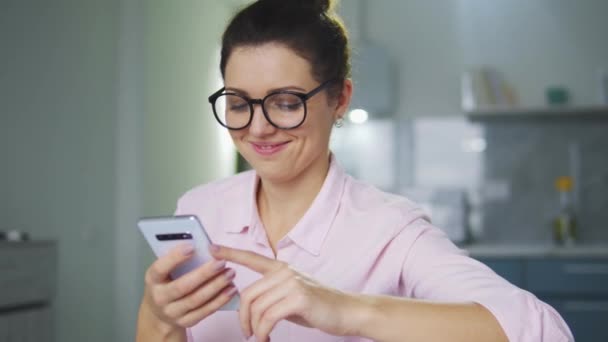 ヘアパンを持つ魅力的な若い女性とスタイリッシュなメガネの笑顔 彼女のスマートフォン上の仕事のオファーとの手紙を受け取ります 簡単に特別なアプリで彼女の欠員に適した選択 — ストック動画