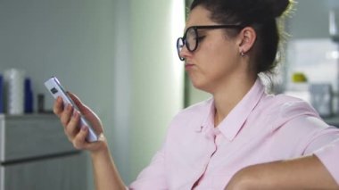 Şık gözlüklü, üzgün akıllı telefon ekranına bakan, bankacılık başvurusunda kredi kartı bakiyesini kontrol eden, para yokluğu, düşük gelir düzeyi, iflas