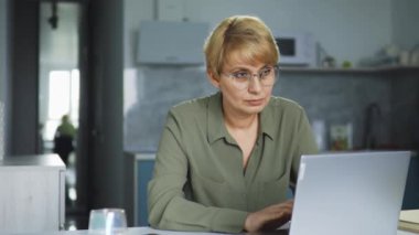 Ciddi, kendine güvenen, gözlüklü bir kadın psikoloğun evde dizüstü bilgisayarla çalışması, online danışmanlık yapması, tavsiye vermesi, insanların korku ve komplekslerle başa çıkmasına yardım etmesi.