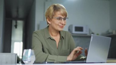 Sarı saçlı, şık gözlüklü, gülümseyen, dizüstü bilgisayarda yazan, iş yazışmaları yapan müşterileri işbirliğine davet eden, müşteri tabanını genişletmeye çalışan olumlu yetişkin kadın sekreter.
