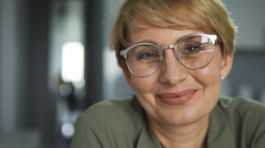 Gözlüklü mutlu bir kadın kameraya sağlıklı bir gülümseme ve taze bir nefes ile poz veriyor, ağız bakımı, diş protezleri ve estetik güzellik kliniği, yakın çekim