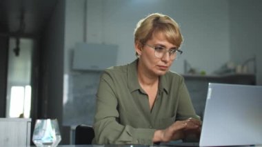 Kaygılı kadın sekreter dizüstü bilgisayarda yazarken bileğinde ağrı hissediyor, uyuşmuş ele masaj yapıyor, klavye ve fare ağrısı çekiyor, kas yorgunluğu ya da karpal tünel sendromu geçiriyor.