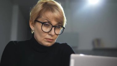 Olgun kadın ofis çalışanı dayanılmaz bir baş ağrısı hissediyor. Geç saatlere kadar bilgisayarla çalışıyor.