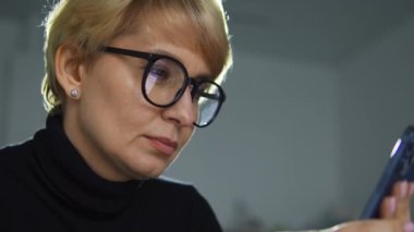 Gözlüklü, bankacılık başvurusunu akıllı telefondan kullanan, fatura ya da para cezası ödeyen, kredi hesabını kontrol eden, malları internetten ayırtan, yemek siparişi veren ve kolay yoldan taksi çağıran sarışın bir kadın.