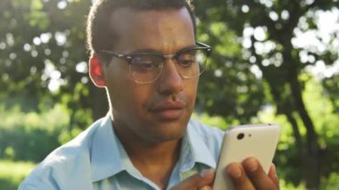 Pozitif heyecan verici çok ırklı bir adam akıllı telefon ekranına bakarak evet hareketi yapıyor, spor ve kazanmaya bahis oynuyor, online açık arttırmaya katılıyor, indirimli fiyattan hisse alıyor, e-ticaret yapıyor.