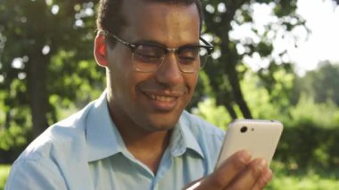 Akıllı telefonda yazı yazan mutlu, çift ırklı bir adam, özel bir uygulama ile online bahis oynuyor ve kazanıyor, serbest dönüşler ve hareketler, gerçek para ya da kripto para, dijital para kazanma yolu