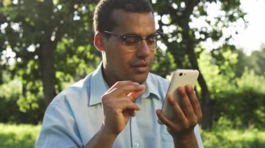 Gözlüklü komik melez adam dans ediyor ve yüksek sesle şarkı söylüyor. Özel bir müzik çalar ya da radyo programında akıllı telefondan müzik dinliyor, web sayfalarını kaydırıyor ya da sesli videolar izliyor.