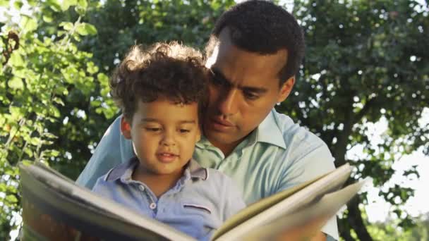 Багатоетнічний Батько Син Читають Велику Книгу Казками Обговорюють Сюжет — стокове відео