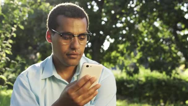 Bonito Homem Biracial Óculos Lendo Mensagem Smartphone Voz Alta Sorrindo — Vídeo de Stock