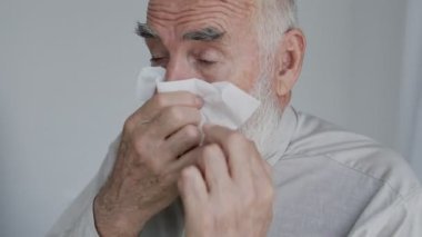 Hasta yaşlı adam peçeteye hapşırıyor, soğuk algınlığı ya da grip, mevsimsel alerji