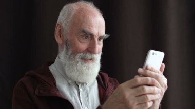 Neşeli emekli adam başarılı bir jest yapıyor, telefonu tutuyor, kredi başvurusu yapıyor.