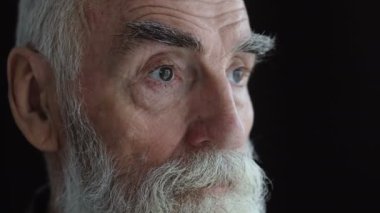 Siyah arka plandaki dalgın yaşlı adam, hayal kırıklığına uğramış, bunalımda.