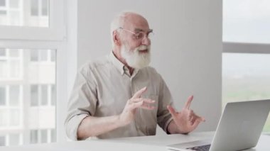 Gri saçlı, sakallı, dans eden, dizüstü bilgisayarı olan başarılı bir adam.