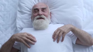 Mutlu emekli adam yatakta kestiriyor, çarşafla örtüyor, evde dinleniyor.