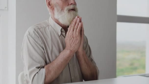 戴眼镜 留着灰胡子的成熟男人 坐着祈祷 — 图库视频影像