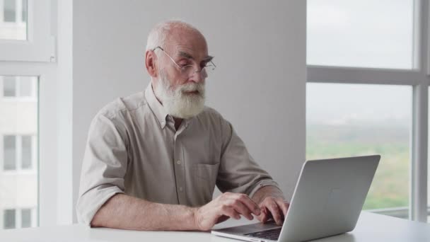 Ηλικιωμένος Γκρι Γενειοφόρος Παππούς Που Εργάζονται Φορητό Υπολογιστή Προσπαθώντας Αντιμετωπίσει — Αρχείο Βίντεο