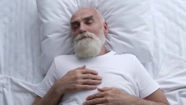 穏やかな静かな睡眠 快適なベッドと枕 老人は一人で白いベッドで寝る — ストック動画