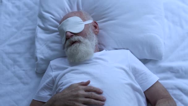 夜にベッドで休んで目のマスクの高齢者の男性 不安睡眠 悪い夢 — ストック動画