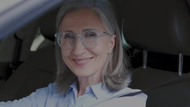 正のシニア女性のカメラを見て笑顔 車の中で座って クレジット — ストック動画