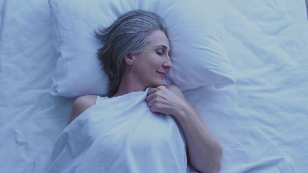 幸せな健康的な成熟した女性は彼女の居心地の良いベッドで寝て 快適な睡眠条件 — ストック動画