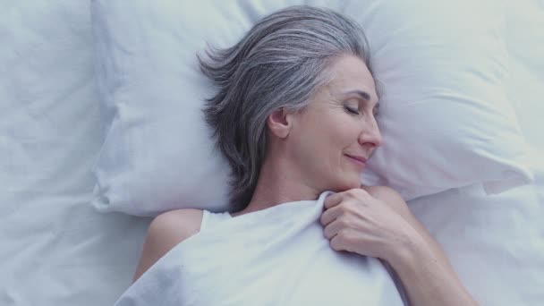 シニア灰色の髪の女性ターニング頭冷静に彼女のベッドで寝て 甘い夢 — ストック動画