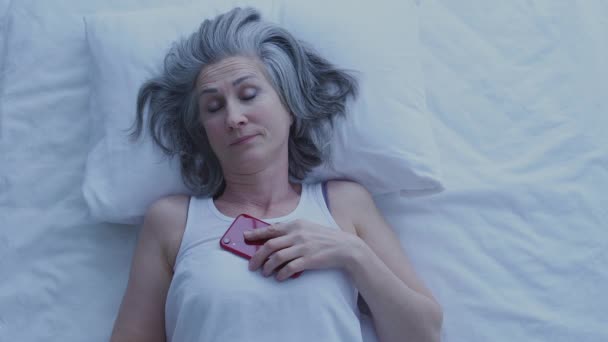 美丽而紧张的女人在床上想着做决定 拿着智能手机 — 图库视频影像