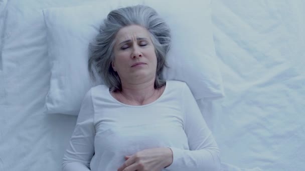 女性は首の痛みを感じ 不快なマットレスと枕に横たわって — ストック動画
