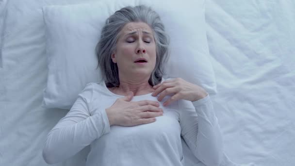 夜のベッドに横たわっ胸の痛みに苦しんでいる病気の女性 — ストック動画