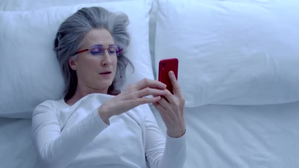 大人の女性のあくび 枕の上にスマートフォンを置く 眼鏡を取る 残りの部分 — ストック動画