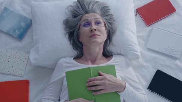 シニア白髪の女性取っ睡眠薬でベッドの上に置くアイマスク — ストック動画