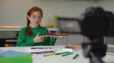 Küçük kız blogger renkli pastel boya setine video eleştirisi kaydediyor.