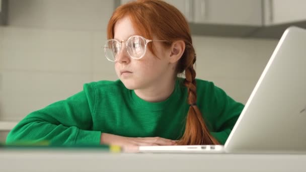 宿題をする代わりに窓を見て夢を見る小さな赤い髪の女の子 — ストック動画